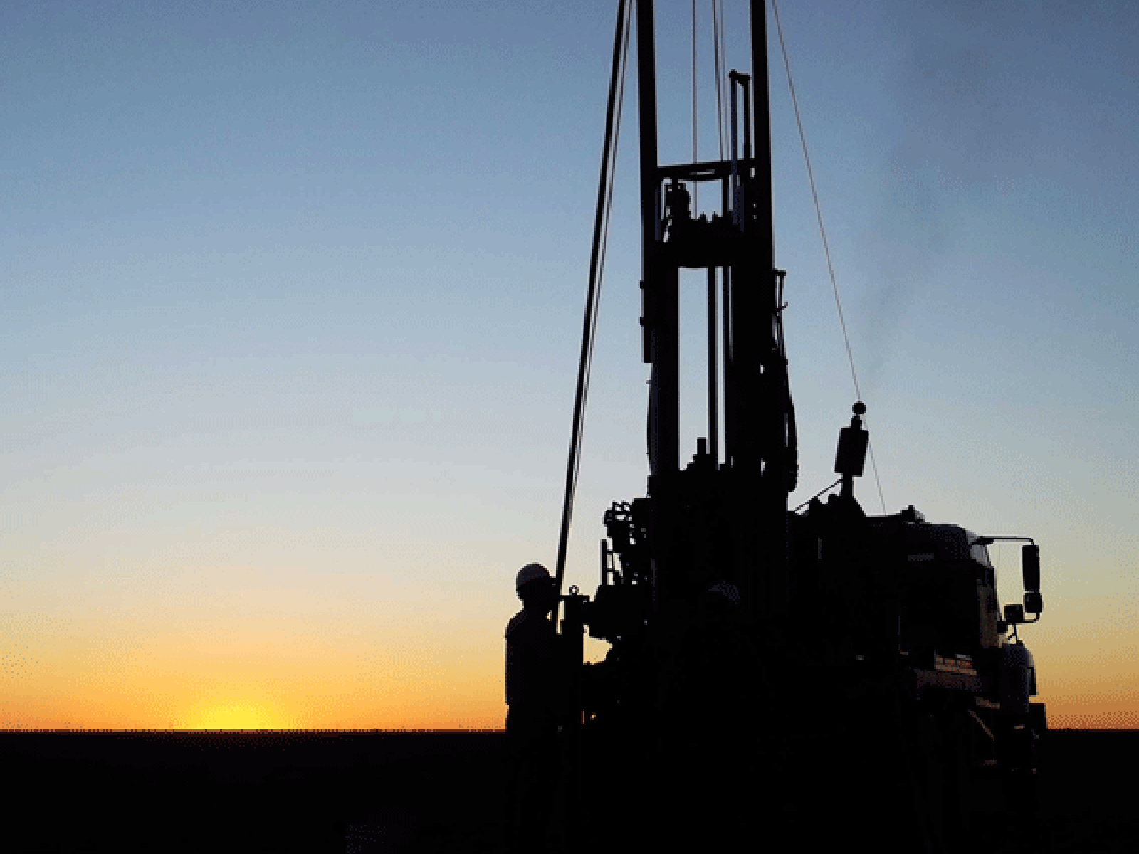 Silhouette of an oil drill rig against the sunset