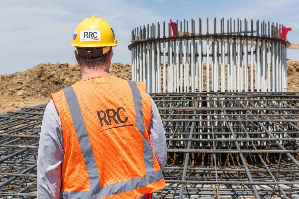 RRC employee in safety gear inspecting rebar foundation cage of wind turbine
